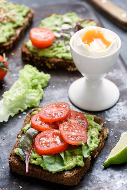Тост с авокадо с капустой и помидорами и вареным яйцом. Здоровый зеленый овощной сэндвич
 - Фото, изображение
