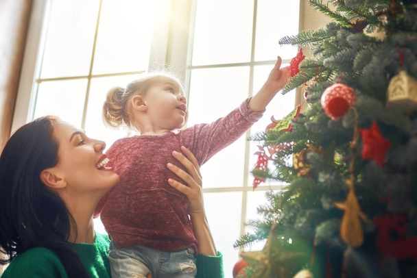 Mom and daughter decorate Christmas tree - Valokuva, kuva