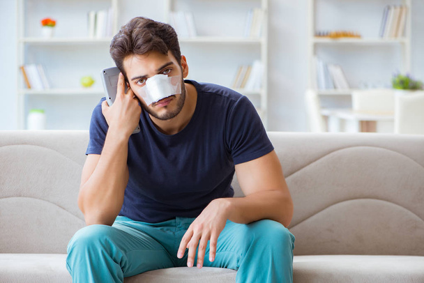 Młody mężczyzna odzyskuje zdrowie w domu po operacji plastycznej nosa - Zdjęcie, obraz