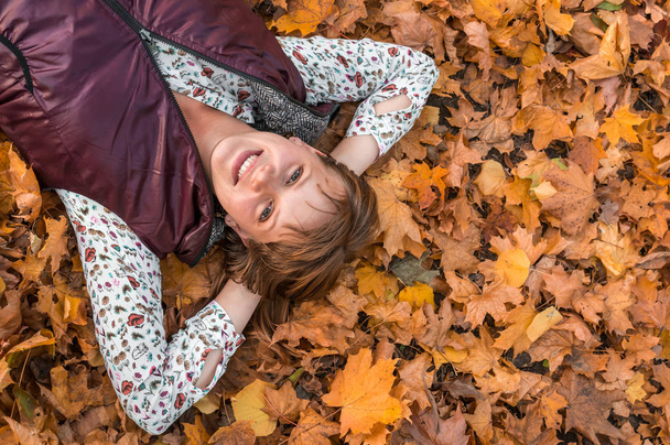 Houkutteleva nainen makaa yli syksyn lehdet puistossa
 - Valokuva, kuva