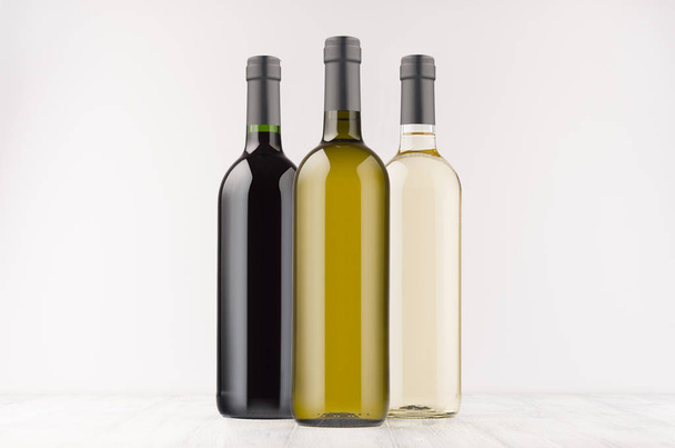 Set wine bottles  different colors - transparent, green, black- on white wooden board, mock up.  - Fotoğraf, Görsel