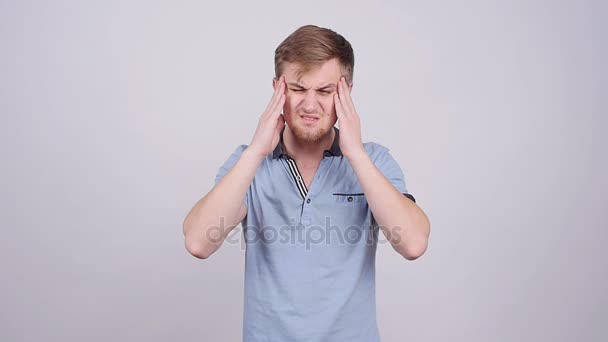 Young man with a headache on a gray background - Footage, Video