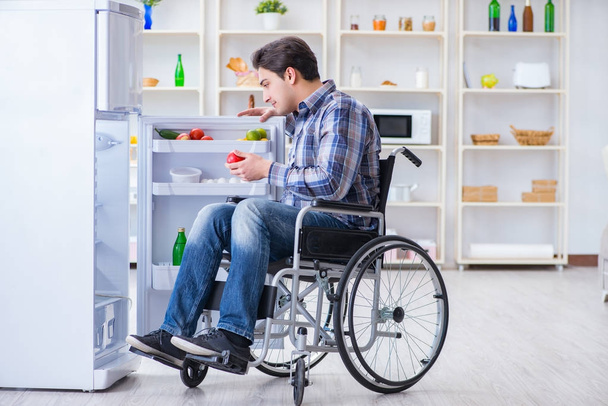 Young disabled injured man opening the fridge door - Photo, Image