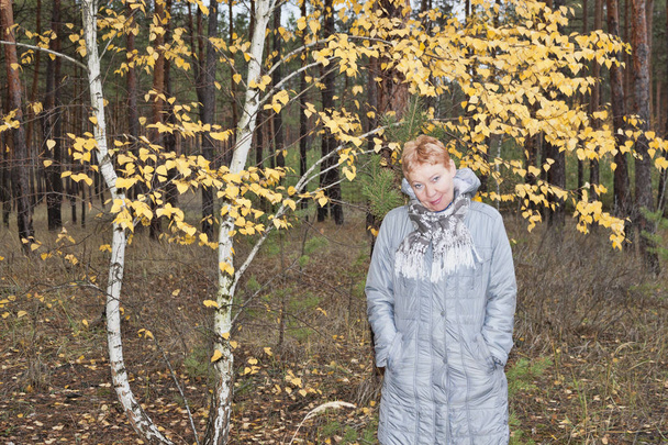 Mature woman near the autumn birch  - Photo, image