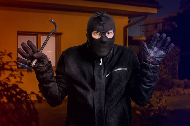 Арестованный вор в маске в балаклаве с ломом и поднятыми руками
 - Фото, изображение