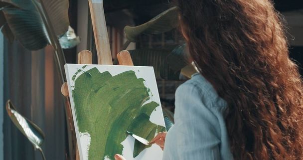 Cute red-haired girl paints in her studio - Photo, Image