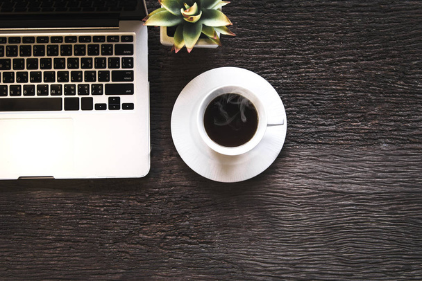 Tasse Kaffee mit Arbeit im Laptop, morgens auf einem alten Holztisch. Lifestylekonzept - Foto, Bild