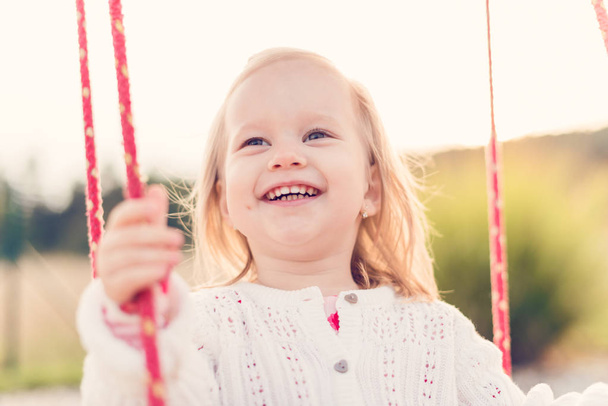 Little girl swinging on a playground. Childhood, Freedom, Happy, Summer Outdoor Concept - Foto, immagini