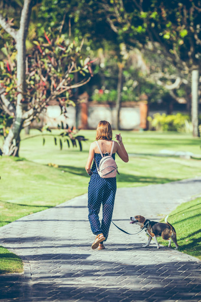 Young woman with her lovely beagle dog in the park of Bali island, Indonesia. - Fotó, kép