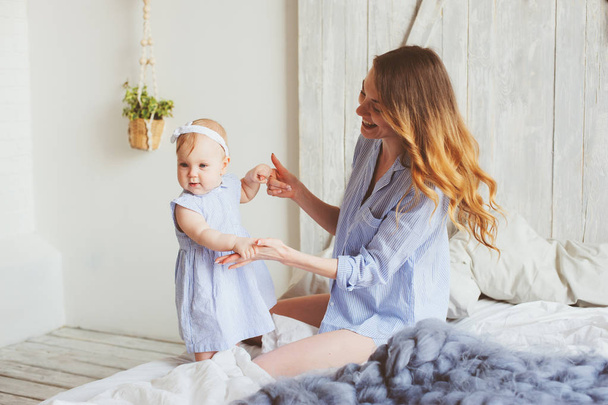 mère heureuse et bébé de 9 mois en pyjama assorti jouant dans la chambre le matin. Week-end familial confortable
. - Photo, image