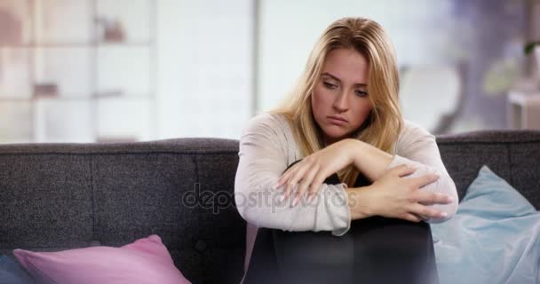 Sad young woman sitting on the couch holding her arms in front of her - Felvétel, videó