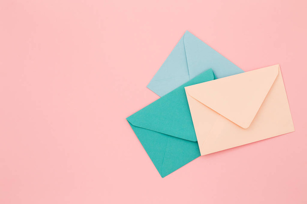 Three colored envelopes on pink background. - Фото, изображение