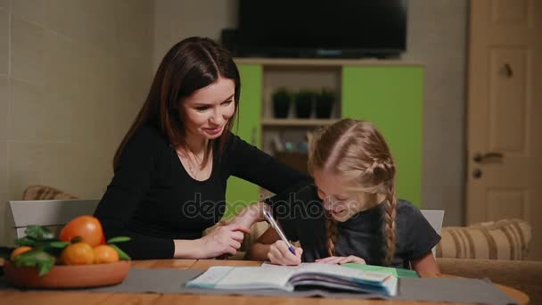 Mutter und Tochter machen Hausaufgaben. Mama hilft, damit umzugehen. - Filmmaterial, Video