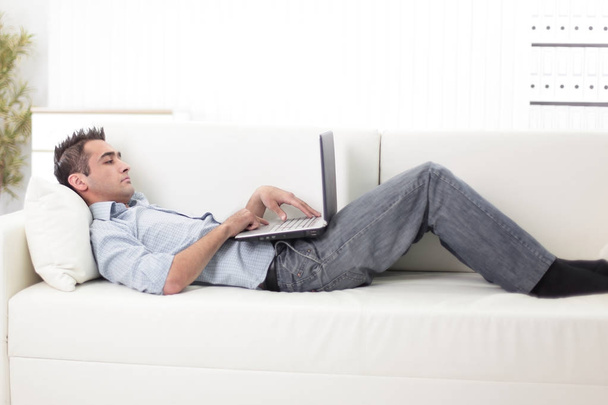 guy with laptop lying on the sofa - Zdjęcie, obraz