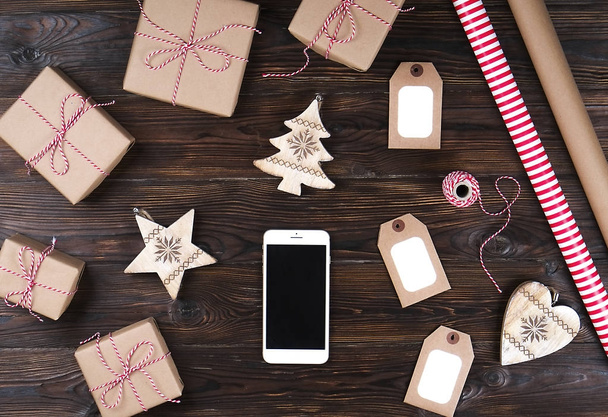 Smart phone with christmas presents on wooden background top view. Online holiday shopping concept. Flat lay, text space. Internet commerce on winter holidays concept. - Fotografie, Obrázek