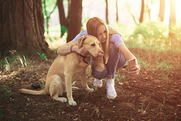 girl making selfie with a dog golden retriever outdoor - Photo, Image