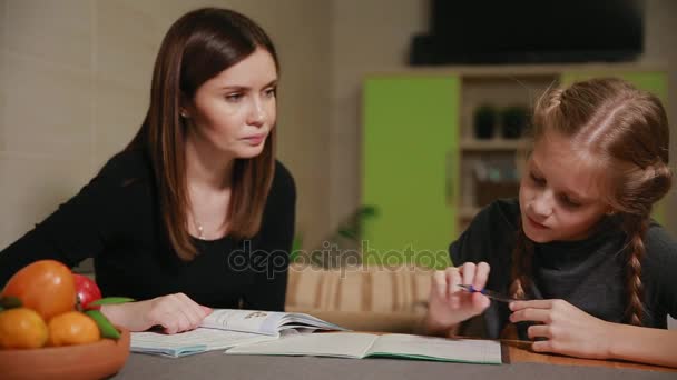 Μητέρα και κόρη κάνουν μια σχολική εργασία. Η μαμά βοηθά να ασχοληθεί με το θέμα. - Πλάνα, βίντεο