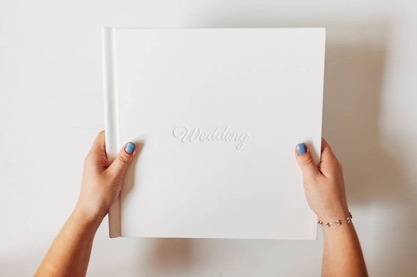 Witte klassieke bruiloft boek op witte achtergrond. Vrouwelijke hand hebt van een boek - Foto, afbeelding