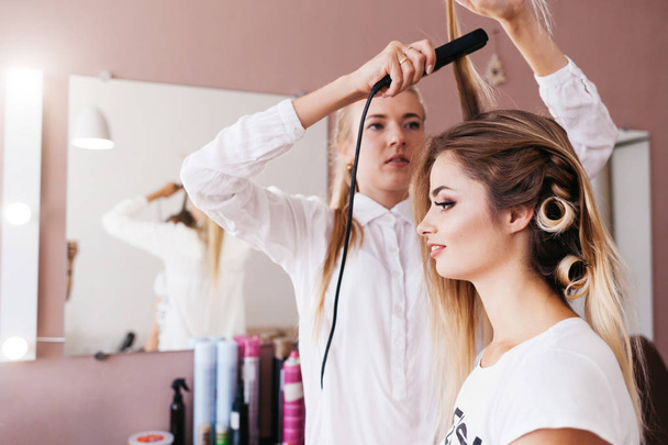 Female hairdresser making hairstyle to brown hair woman in beauty salon - Photo, Image