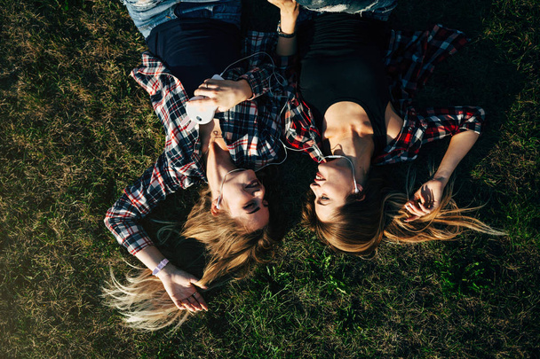 sisters lying on grass in park - Zdjęcie, obraz