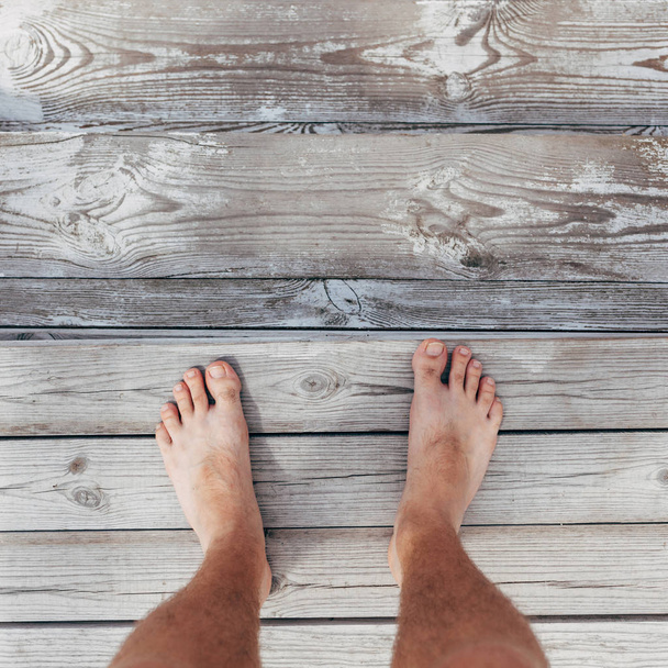 Top view shot of male feet on wooden background - Photo, image