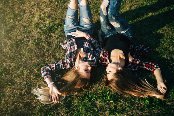 sisters lying on grass in park - Foto, afbeelding
