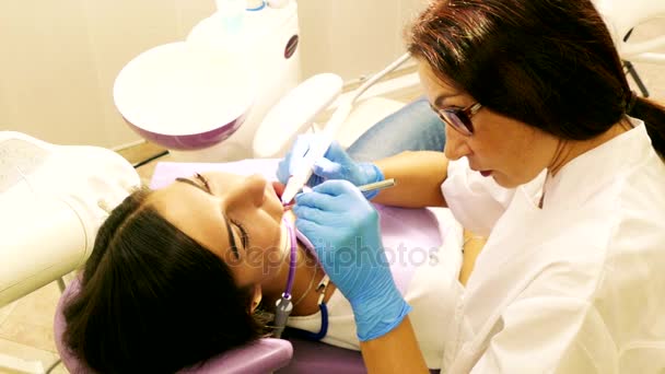 Οδοντίατρος στο έργο στην οδοντιατρική μονάδα με μια νεαρή γυναίκα ασθενή - Πλάνα, βίντεο