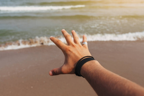 Man's hand on a background of the sea - Photo, Image