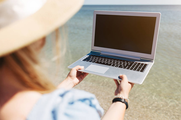 Młoda piękna kobieta siedząca z laptopem na plaży, w pobliżu morza - Zdjęcie, obraz