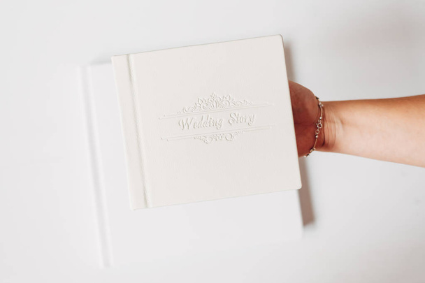 Libro clásico blanco de la boda en fondo blanco. Mano femenina sosteniendo un libro
 - Foto, Imagen
