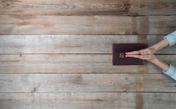 Woman hands holding a bible over a desk.  - Fotó, kép