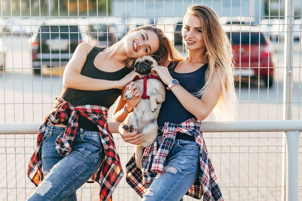sestry-dvojčata spolu v parku s roztomilý Mops pes - Fotografie, Obrázek