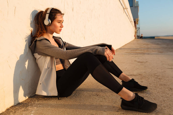 Young pretty runner woman resting after run, listening to music  - Foto, imagen