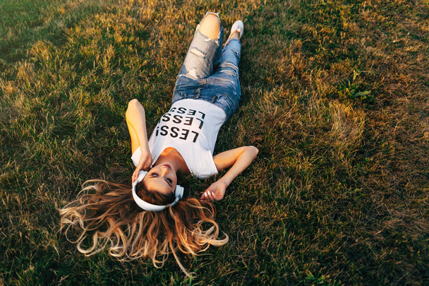 ヘッドフォンで草の上に横たわる女 - 写真・画像