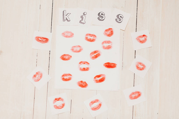 Top vista tiro de composição com impressões de batom vermelho no papel e beijo de texto em fundo de madeira
 - Foto, Imagem