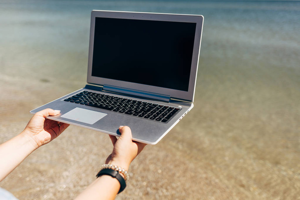 Laptop w męskie ręce na tle błękitnego morza - Zdjęcie, obraz