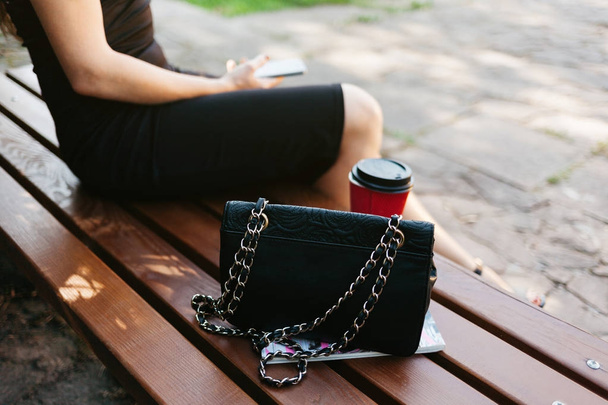 femme assise sur un banc avec café et sac à main
 - Photo, image