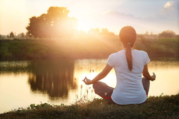 Молодая женщина йога практикует и медитирует на озере летом
 - Фото, изображение