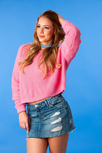 Beautiful young woman in jeans skirt and pink sweater - Photo, image