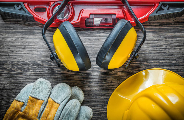 Construction level safety gloves hard hat earmuffs on wooden boa - Foto, imagen