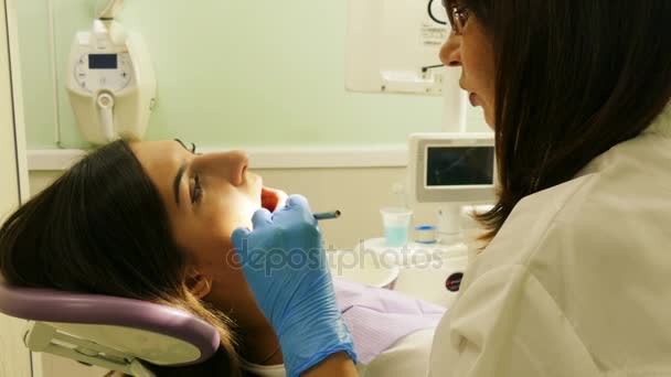 Οδοντίατρος στο έργο στην οδοντιατρική μονάδα με μια νεαρή γυναίκα ασθενή - Πλάνα, βίντεο
