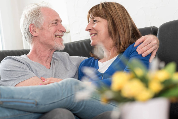 Szczęśliwa para starszy siedzi na kanapie i w objęciach - Zdjęcie, obraz