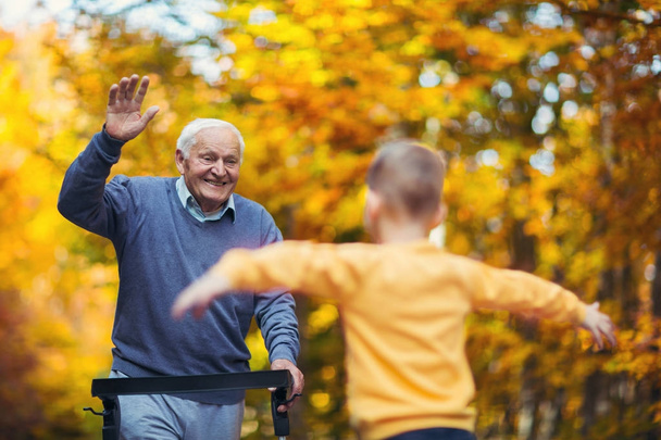 Cheerful avô deficiente em walker acolhendo seu neto feliz
 - Foto, Imagem