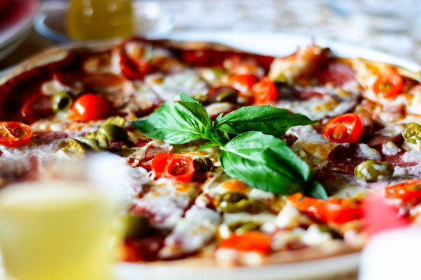 Maukas pizza vihanneksilla, lihalla ja kastikkeilla kahvilassa valkoisella lautasella. Sulje se.
. - Valokuva, kuva