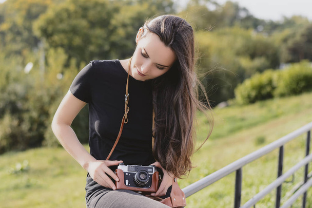 Young happy female photographer walks in the Park with retro camera - 写真・画像