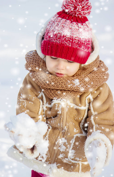 Ένα παιδί παίζει στο χιόνι το χειμώνα. Επιλεκτική εστίαση. - Φωτογραφία, εικόνα