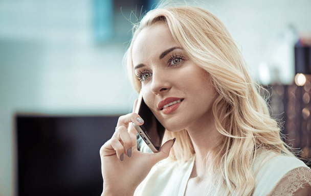 Closeup portrait of a pretty blonde using a smartphone - Valokuva, kuva