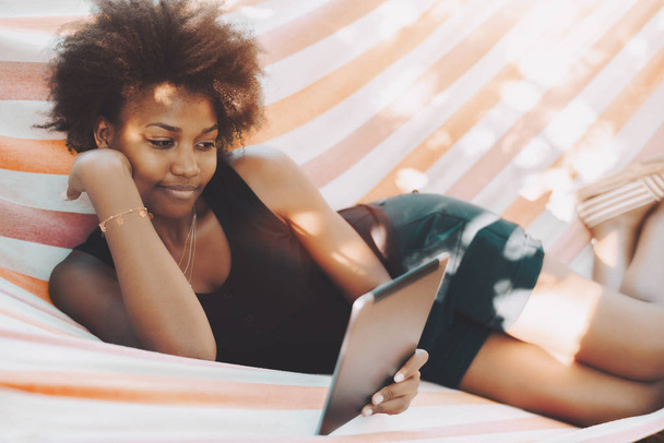 Κορίτσι Αφρο σε αιώρα με ψηφιακή μαξιλάρι - Φωτογραφία, εικόνα