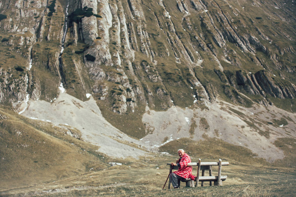 Vanhempi mies istuu penkillä vuorella.
 - Valokuva, kuva