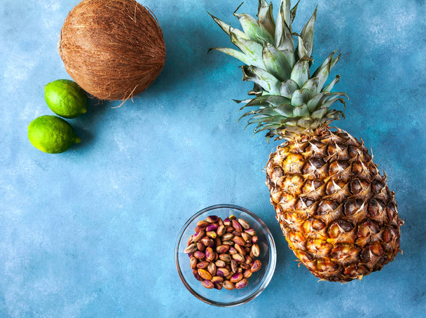 pineapple, coconut, lime and pistachios on a blue background of  - Фото, изображение